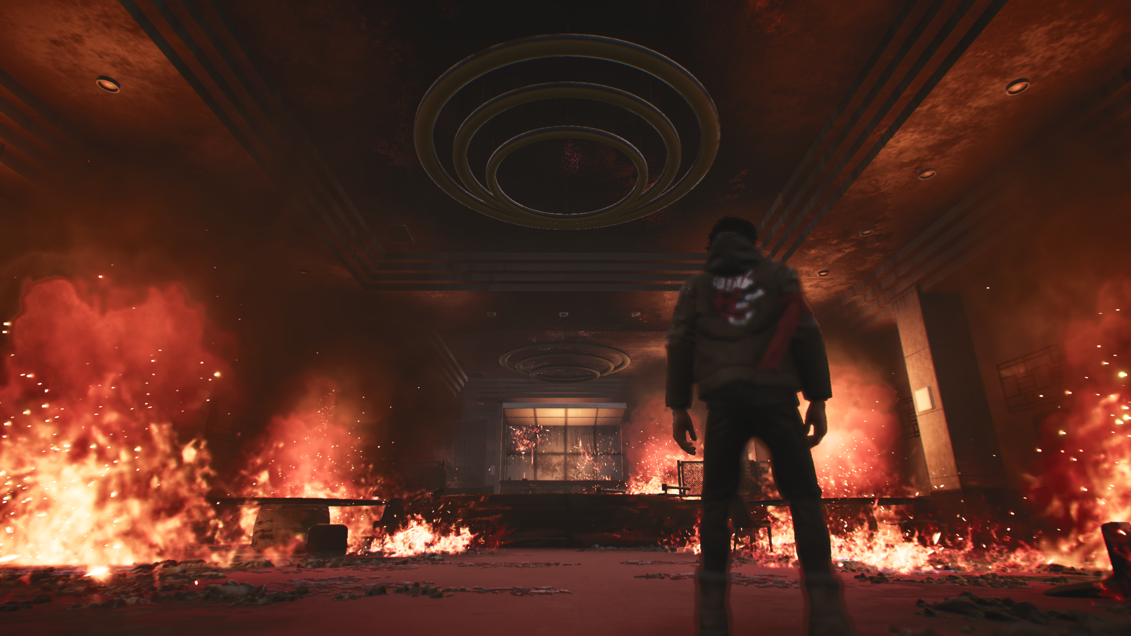 Hendra stands in a damaged hallway surrounded by fire and smoke.